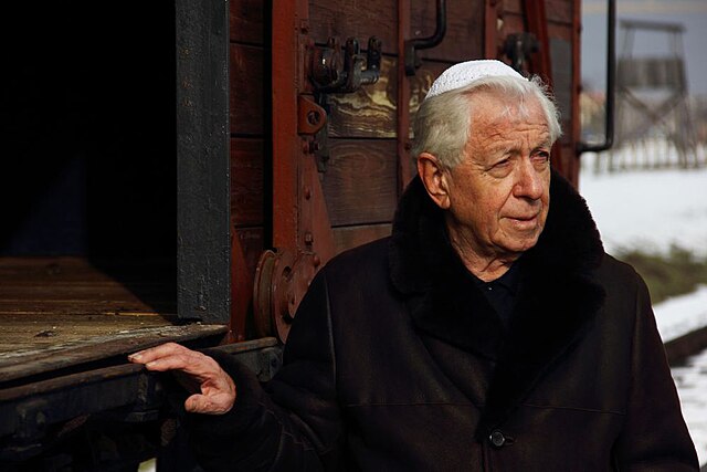 Lowy at the 2013 March of the Living in Auschwitz-Birkenau in front of the cattle car donated in memory of his father, Hugo.
