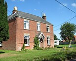 Two story brick house with two chimneys and a front lawn