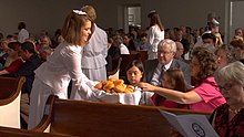 Female dieners in the Moravian Church serving bread to fellow members of their congregation during the celebration in a lovefeast are seen wearing headcoverings. Lovefeast at Bethania Moravian Church.jpg