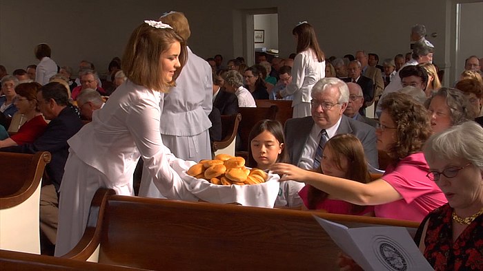 A Moravian diener serves bread to fellow members of her congregation during the celebration of a lovefeast.