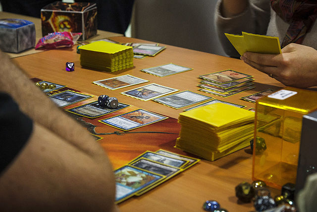 Players engaged in a game of Magic: The Gathering with sleeved cards