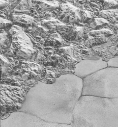 Solid nitrogen on the plains of Sputnik Planitia (on the bottom-right side of the image) on Pluto next to water ice mountains (on the up-left side of the image) Mountainous Shoreline of Sputnik Planum (PIA20198).png