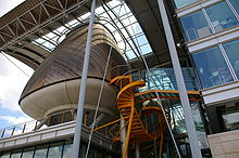 Photographie d'un bâtiment moderne composé de plusieurs parties, en verre et en bois.