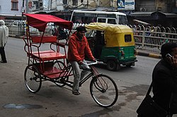 Egy ciklikus riksa és egy autós riksa látható Delhi egyik utcájában