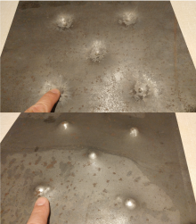 Swebor-brand high-strength low alloy steel plate, showing both sides, after plastic deformation from bringing to rest projectiles in ballistics testing. Pannzerung plastische deformation.png