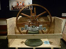 Photo of a large metal bell and its circular wooden support in a half unpacked crate The Mears Bell after repairs