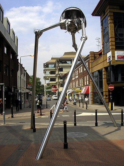 An art installation in Woking depicts a tripod and (out of picture) a Martian Cylinder. "The Woking Martian"; Michael Condron, 1998