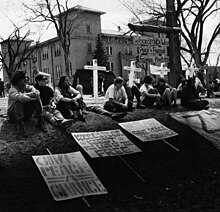 Flanked by four crosses bearing the names of students killed by National Guardsmen at Kent State University, University of Denver students protest their own school's decision to stay open. Woodstock West University of Denver 1970.jpg