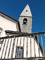 Photographie d'un clocher d'église gris et assez simple, avec une barrière en métal devant.