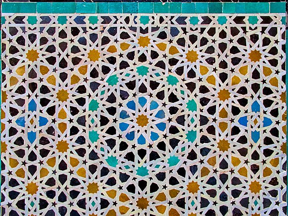 Example of geometric pattern in the Bou Inania Madrasa of Fez. This example employs a fivefold geometric system with 10-pointed stars, while also adding visual diversity through colour.