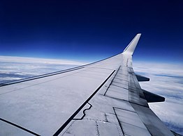 A generic Boeing 737-800 cruising at 32,000 feet. Below it is a pack of clouds. Above it is a vivid, ambient blue sky.
