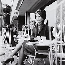 "Jane Seitz in den frühen 1960er Jahren vor einem Café sitzend"