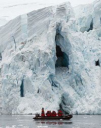 Close-up of zodiac with passengers in front of a section of the glacier for size perspective.