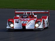 Una vista de un coche deportivo rojo y blanco en una pista de carreras