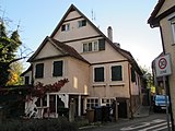 Deutsch: Wohnhaus mit ehemaligem Dorfbad. Eingeschossiger Putzbau über hohem Sockel mit Anbau auf Stützen, 1546 (d), im Keller das bereits im 14. Jahrhundert urkundlich erwähnte Dorfbad mit Kreuzgratgewölbe über 16 Wandpfeilern, dort bezeichnet 1623.