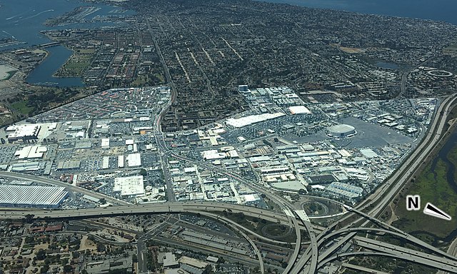 This is an image of Midway District, San Diego that was taken from a low-flying airplane facing approximately southwest. The bordering neighborhoods have been dimmed to distinguish the district boundaries. At the center is the Midway district, part of Old Town is visible at the bottom. In the background at the top left of the image is Liberty Station, and at the top center is Loma Portal.