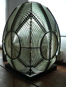 First-order rotating catadioptric Fresnel lens, dated 1870, displayed at the Musee national de la Marine, Paris. In this case the dioptric prisms (inside the bronze rings) and catadioptric prisms (outside) are arranged to concentrate the light from the central lamp into four revolving beams, seen by sailors as four flashes per revolution. The assembly stands 2.54 metres tall and weighs about 1.5 tonnes. MuseeMarine-phareFresnel-p1000466.jpg