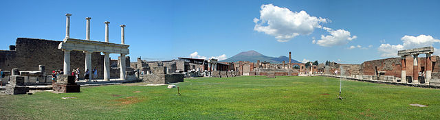 The Forum of Pompeii with the entrances to the Basilica (left) and Macellum (right), the Temple of Jupiter (front) and Mount Vesuvius in the distance.