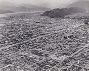 Black and white photo of a destroyed urban area. The outline of a grid pattern of streets is visible, but most buildings have been reduced to rubble.