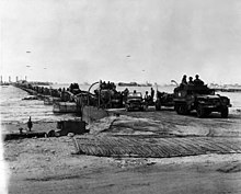 U.S. Army vehicles transit a Seabee assembled causeway off "Mulberry A" at Omaha Beach. US Army vehicles rolling off Mulberry A 16 June 1944.jpg