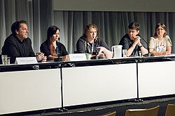 Kuvassa on viisi aikuista ihmistä, jotka istuvat paneelissa pöydän ääressä. Elina Pitkäkangas on kuvassa toisena vasemmalla.