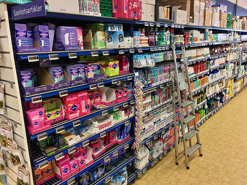 File:Aisle shelves with tampons, women's sanitary towels ("sanitetsartikler"), tooth brushes, health and body care products, etc. in REMA 1000 Supermarket, Osøyro, Hordaland, Norway 2018-03-19.jpg