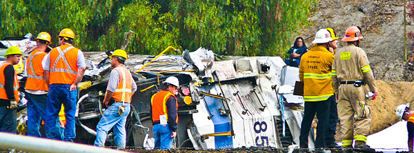 Recovery workers stand near the rear of the Metrolink locomotive after it was removed from the lead passenger car, where most of the serious injuries 