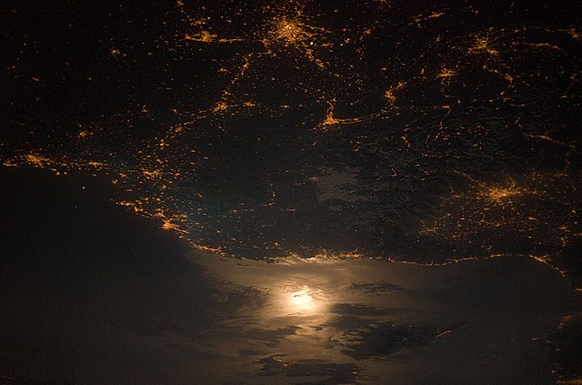 A photograph of the France–Italy border at night. The southwestern end of the Alps separates the two countries.