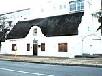 Across the road from the Burgher House, next to the Divisional Council Offices, stands this charming thatched cottage, with its dormer window in front and attractive concavo-convex side gables. Coachman's House, Alexander St, Stellenbosch.jpg