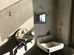 Two sinks in a Tuberculosis ward with the Statue of Liberty reflected in the mirror[84]