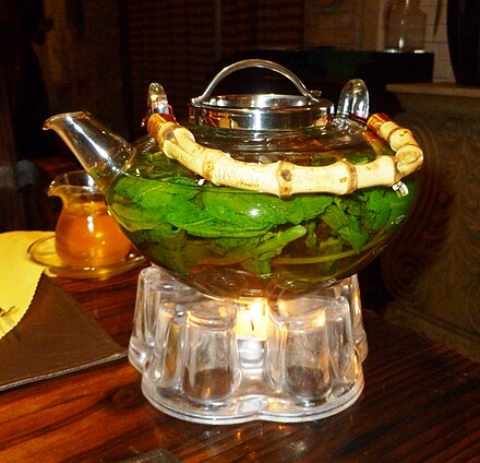 Glass teapot containing mint leaves, being warmed by a tealight, Kashgar, Xinjiang, China