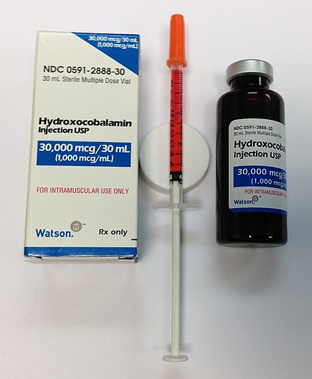 A vitamin B12 solution (hydroxocobalamin) in a multi-dose bottle, with a single dose drawn up into a syringe for injection. Preparations are usually bright red.