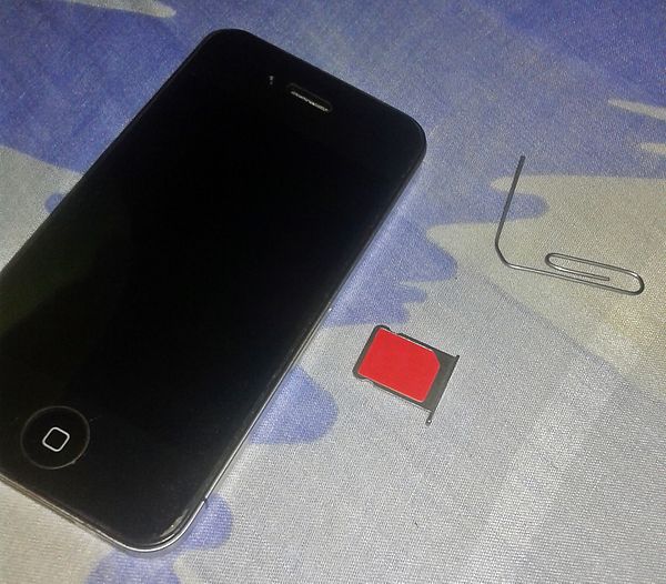 An iPhone 4 A1332 with a micro-SIM card removed with a paper clip, showing its SIM card compartment