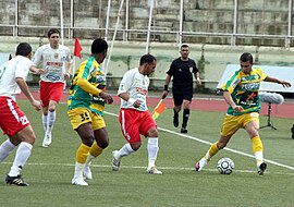 Deux joueurs de football en plein match, un de la JSK l'autre de la JSMB