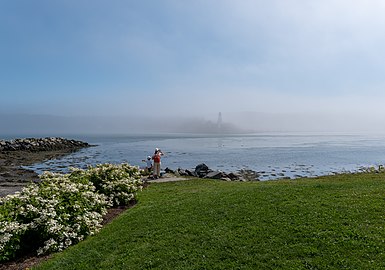 Jules and Gabriel using a set of binoculars to look at Mulholland Point Lighthouse, Lubec, Maine, US