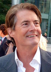 A brown-haired man looking up and smiling.