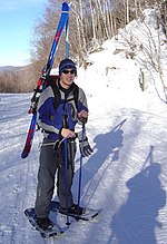 A snowshoer packing downhill skis Snowshoer packing skis.jpg