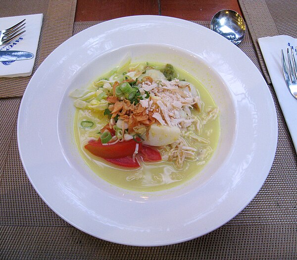 Soto ayam or chicken soto, with yellow coconut milk broth, the slices of lontong, and fried shallot