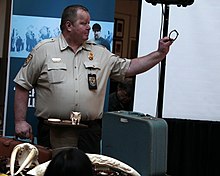 Supervisory Wildlife Inspector Charles "Chuck" Quick holds a confiscated bracelet made of illegal elephant hair Wildlife Inspector (28920833663).jpg