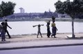 A woman and her two daughters (?) in front of a lagoon and Hotel President in the distance, Yamoussoukro, Côte d'Ivoire, 1980
