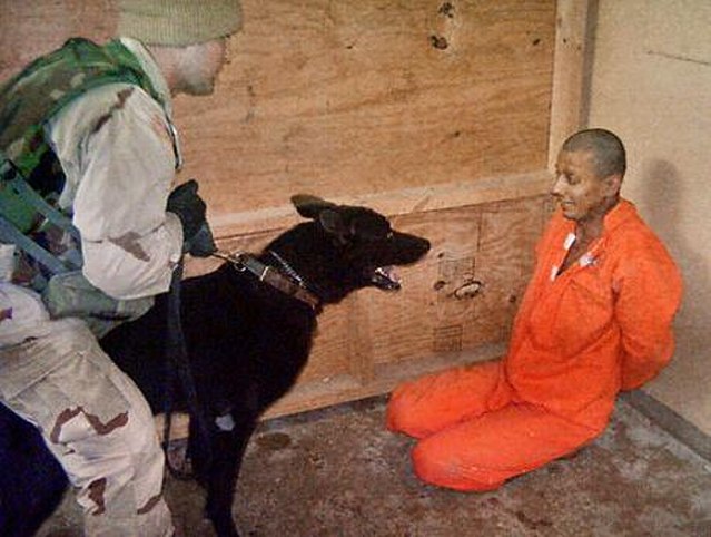 Sergeant Smith, a dog handler, uses a dog to scare a bound prisoner.