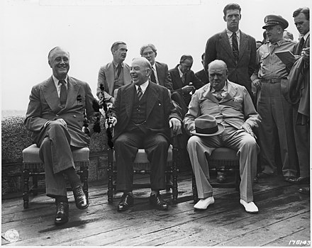 Press Conference at the Citadelle of Quebec during the Quadrant Conference. Left to right: President Franklin D. Roosevelt, Canadian Prime Minister Mackenzie King, and British Prime Minister Winston Churchill. Seated on the wall behind them are Anthony Eden, Brendan Bracken and Harry Hopkins.