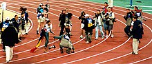 Cathy Freeman surrounded by world media and carrying the Aboriginal and Australian flags following her victory in the 400 m final of the Sydney Olympics, 2000 Cathy400 mediafrenzy.jpg