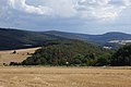 Der Berg Burg von Nordwesten gesehen. Links am Bildrand der Berg Windhain, darüber lugen die Türme des Großen Feldbergs hervor, mittig am Horizont Kleiner Feldberg, sowie davor der Weilsberg, der nach links in den Hühnerberg übergeht, hinten rechts der Glaskopf über den Häusern von Oberems sowie wiederum darunter Wüstems.