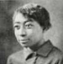 A young Black woman with short hair, wearing a collared shirt
