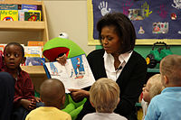 Đệ nhất phu nhân Michelle Obama phát âm Chàng Mèo Mang Mũ mang đến học viên mầm non bên trên Prager Child Development Center, nhập chuyến thăm hỏi Fort Bragg, Bắc Carolina.