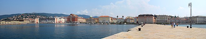 Panorama di Trieste visto dal Molo Audace (spicca il falso storico della copertura del teatro Verdi, allineato alla linea di fuga sinistra del molo, risaltente alla ristrutturazione degli anni '90 del 1900 che ha sostituito il tetto originale costituito da falde piane ricoperte da coppi rossi)