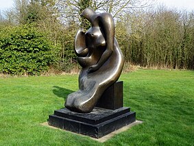 A bronze-coloured sculpture outside, which resembles a mother's body, and her carrying a baby
