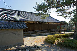 Long wooden building with an open veranda with handrail.