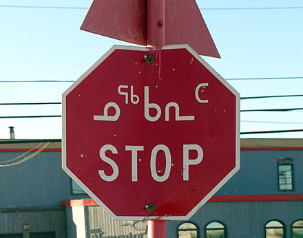 A bilingual stop sign in Nunavut displaying text in both Inuktitut syllabics and the English Latin alphabet. The Inuktitut ᓄᖅᑲᕆᑦ transliterates as nuqqarit.